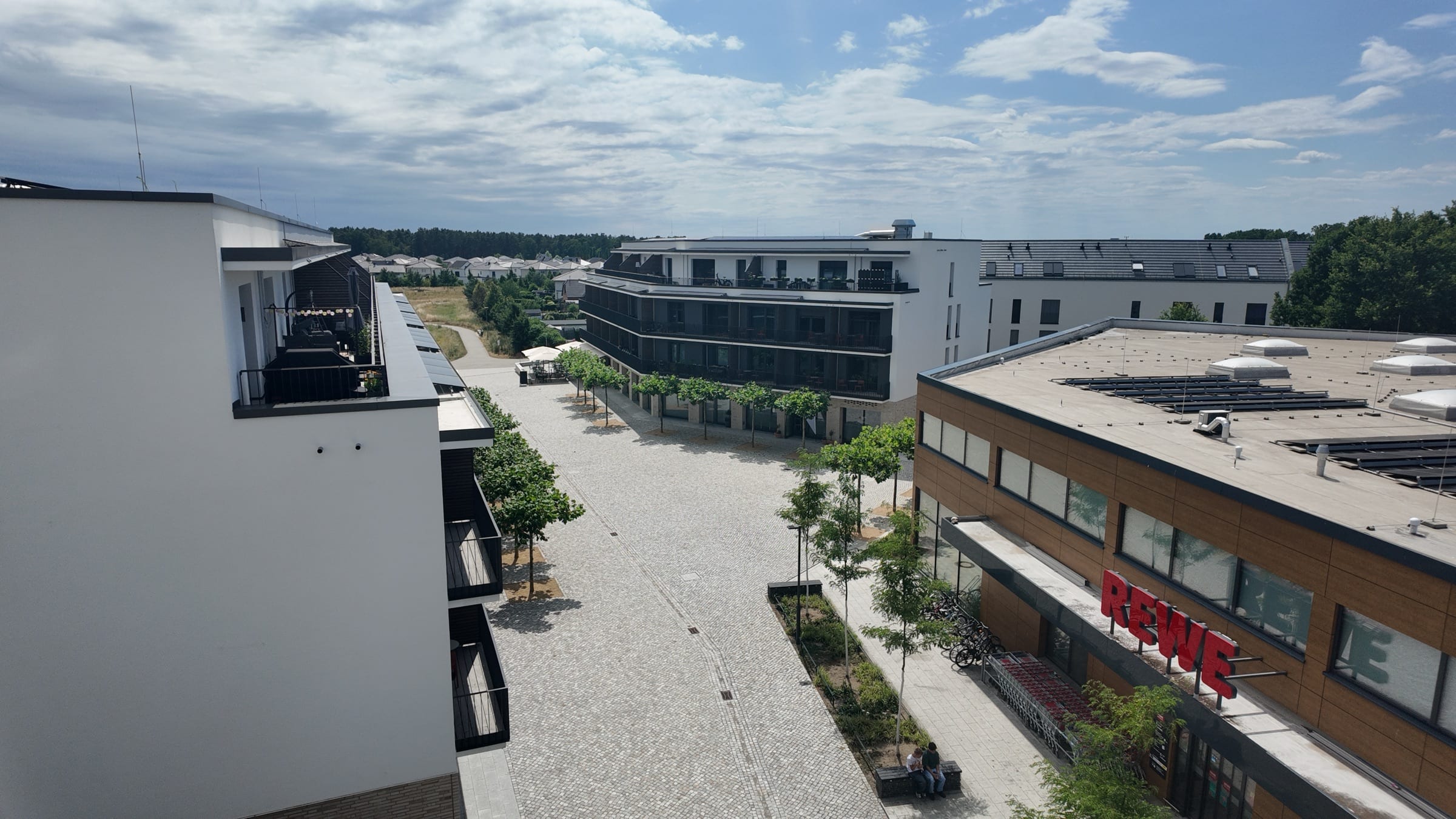 Luftbild des Rousseauplatzes mit REWE, Gewerbeflächen und Wohnbebauung